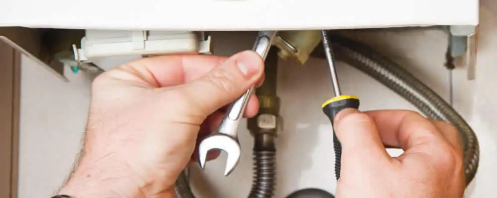 Boiler repair technician tightening pipe fittings and connections in Andover, MA