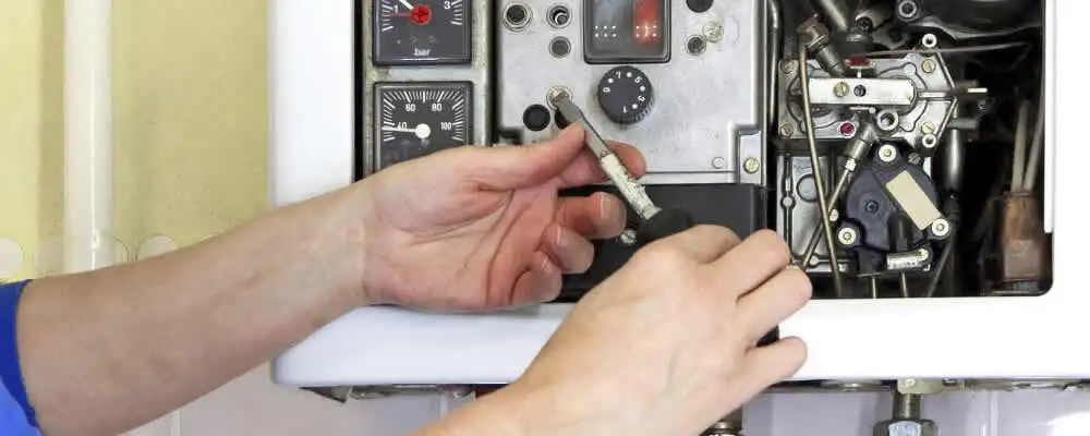 Heating repair technician adjusting boiler controls and components in Andover, MA