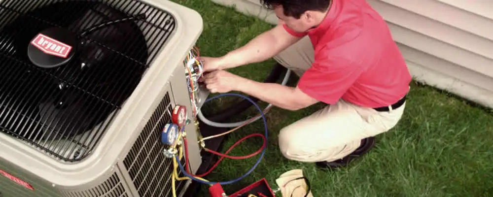 HVAC technician servicing an outdoor air conditioner unit in Andover, MA