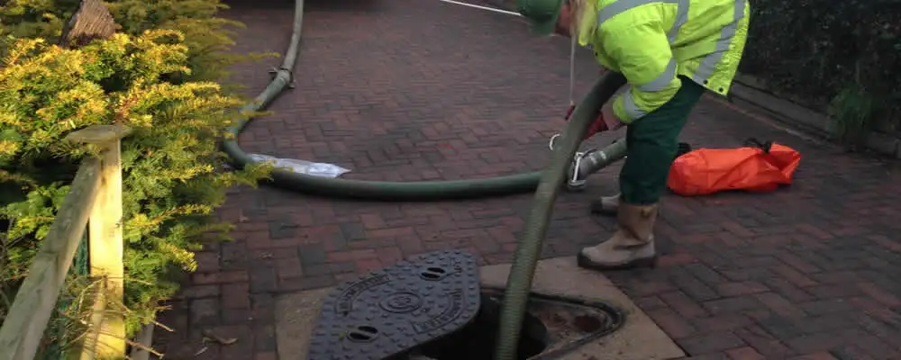 Septic tank cleaning technician servicing a septic tank with a vacuum hose in Andover, MA