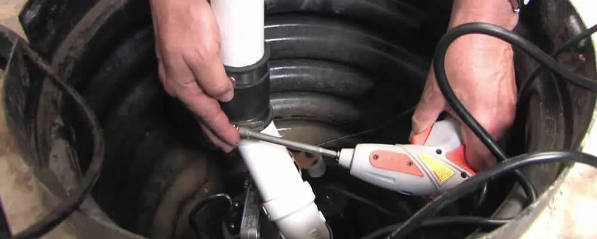Sump pump installation technician connecting PVC discharge piping in Andover, MA