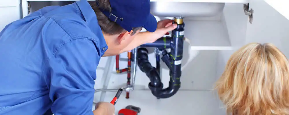 Plumber repairing under-sink drain pipes and fittings in Andover, MA